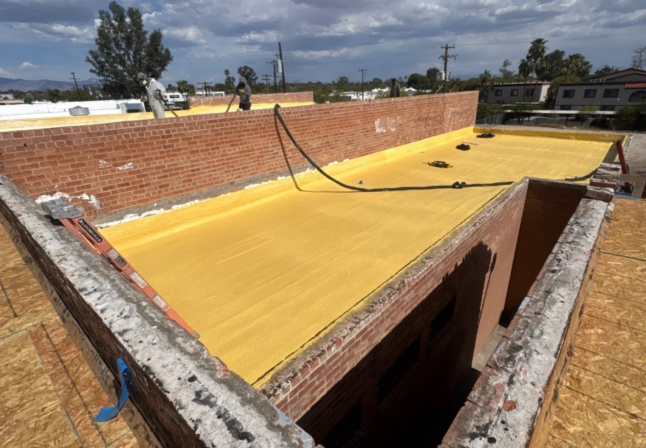 Yellow flat roof membrane installed on commercial building with brick parapets and drainage system