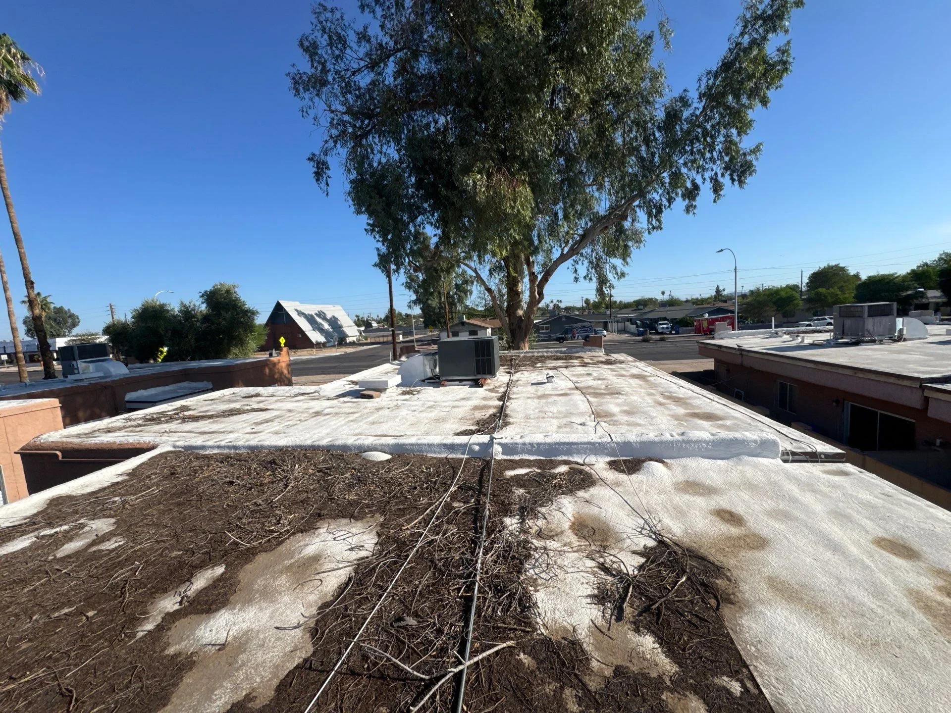 Commercial flat roof with white membrane, drainage lines, and HVAC equipment on industrial building