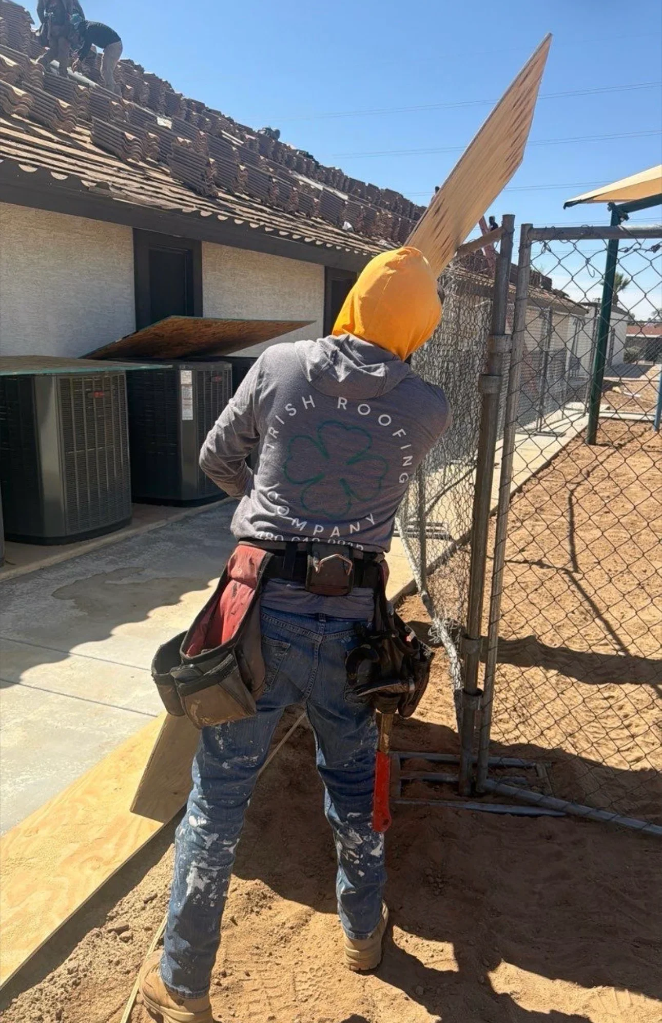 Roofer removing shingles and materials from pitched roof structure during tear-off phase