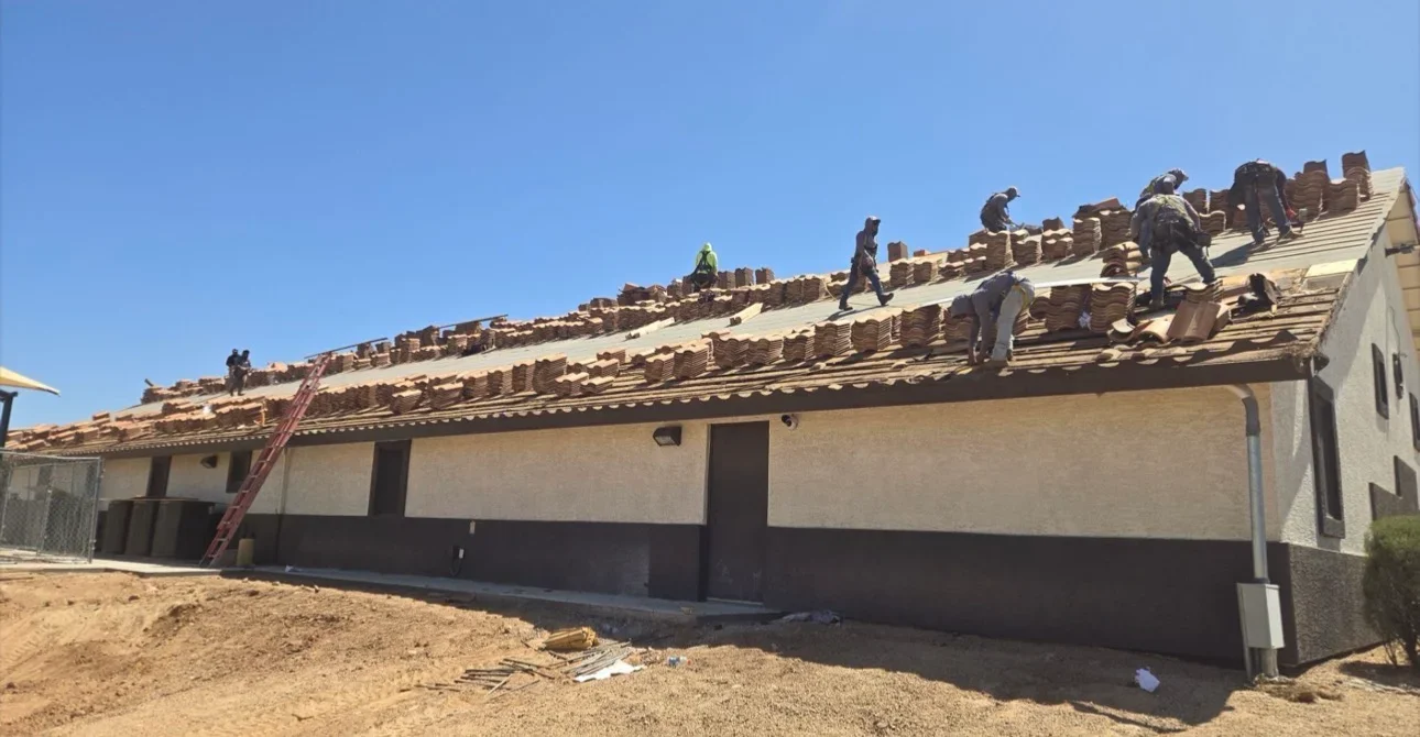 Residential roof replacement with clay tile installation, workers on pitched roof structure