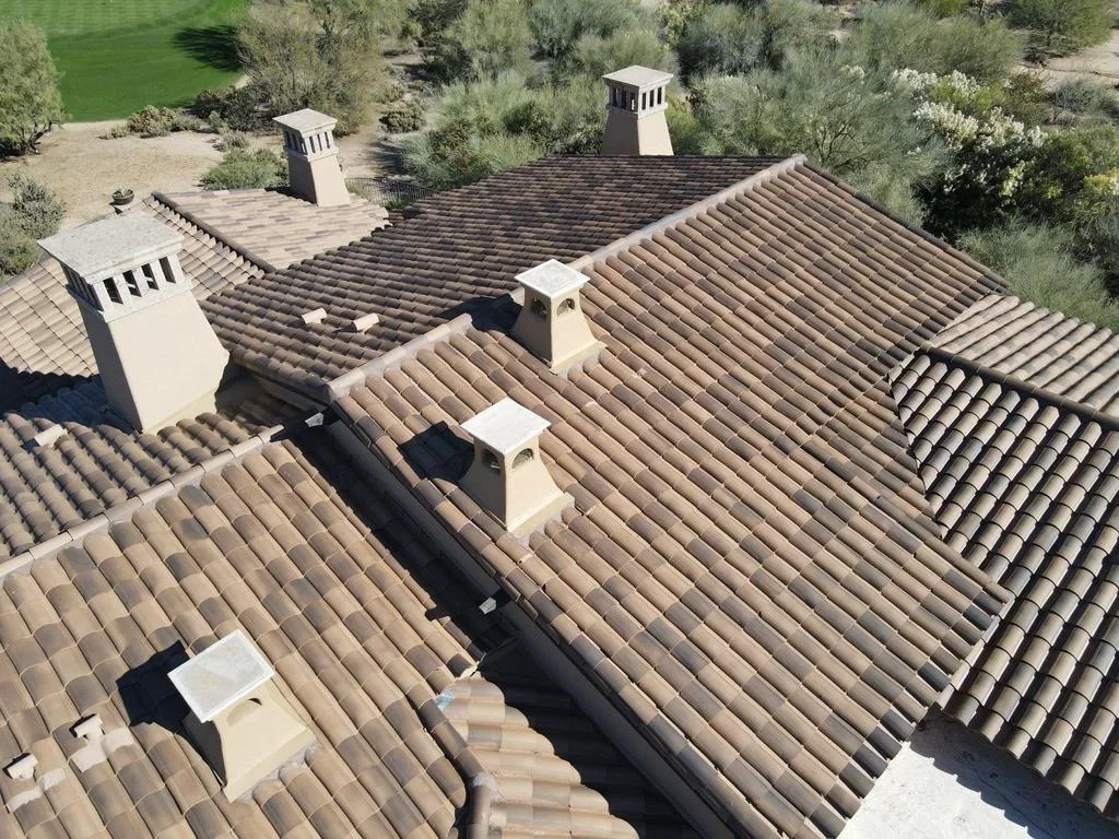Aerial view of Spanish clay tile roof with barrel tiles, multiple chimneys, and white trim caps