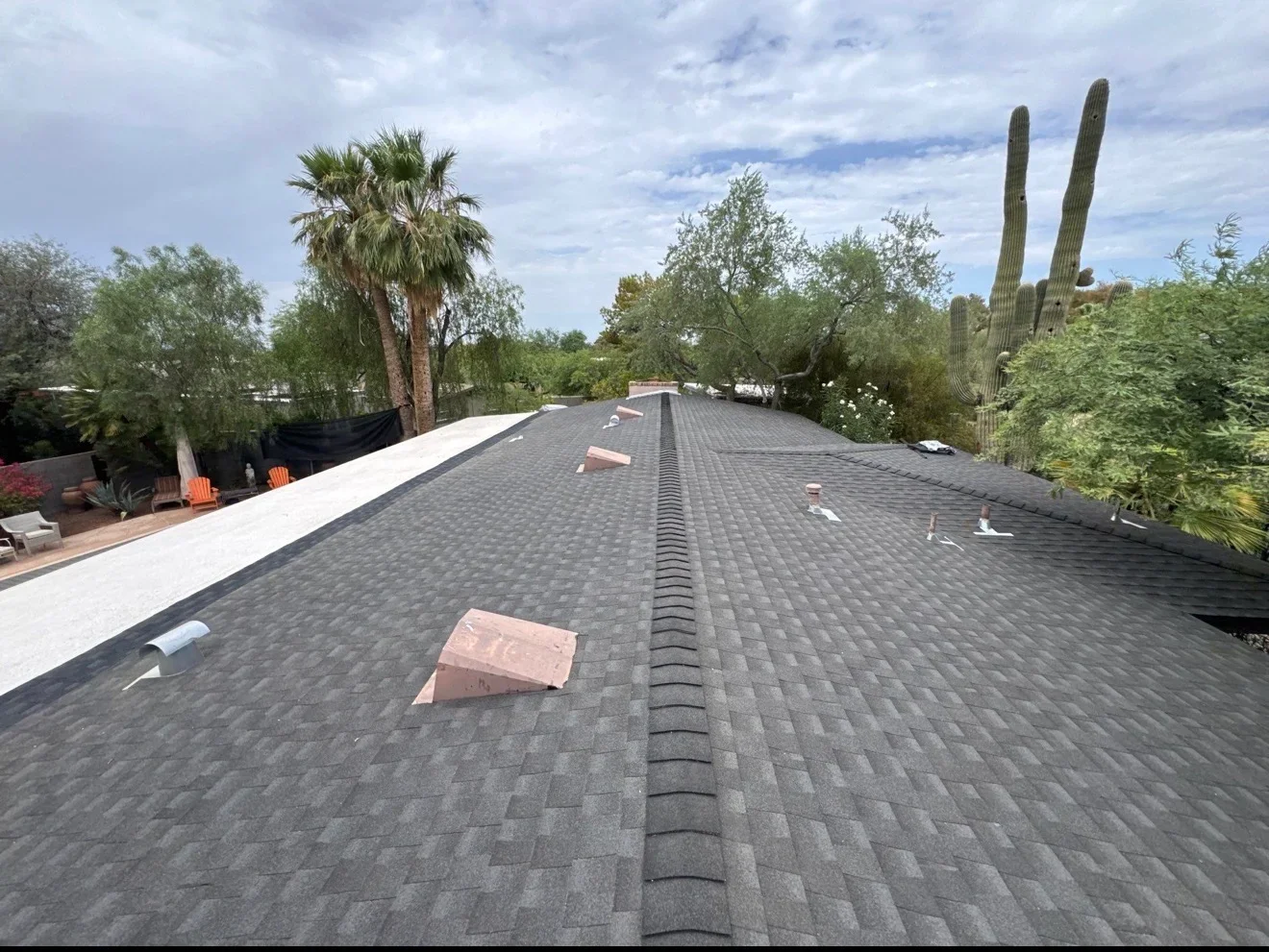 Charcoal asphalt shingle roof with ridge vent and white trim installation in progress
