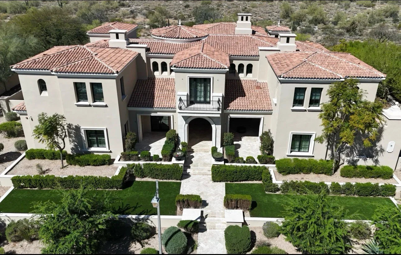 Spanish Colonial estate with terracotta barrel tile roof, white stucco walls, multiple cupolas, and complex roof geometry