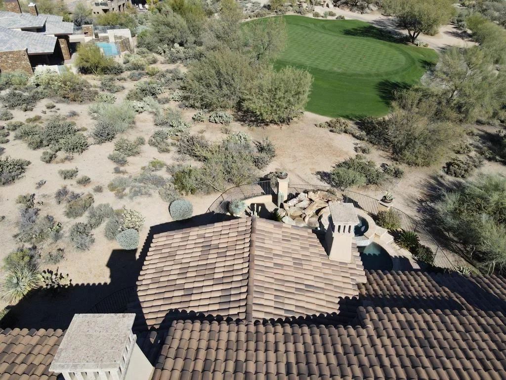 Aerial view of clay tile roof installation with multiple planes and metal railings on desert home