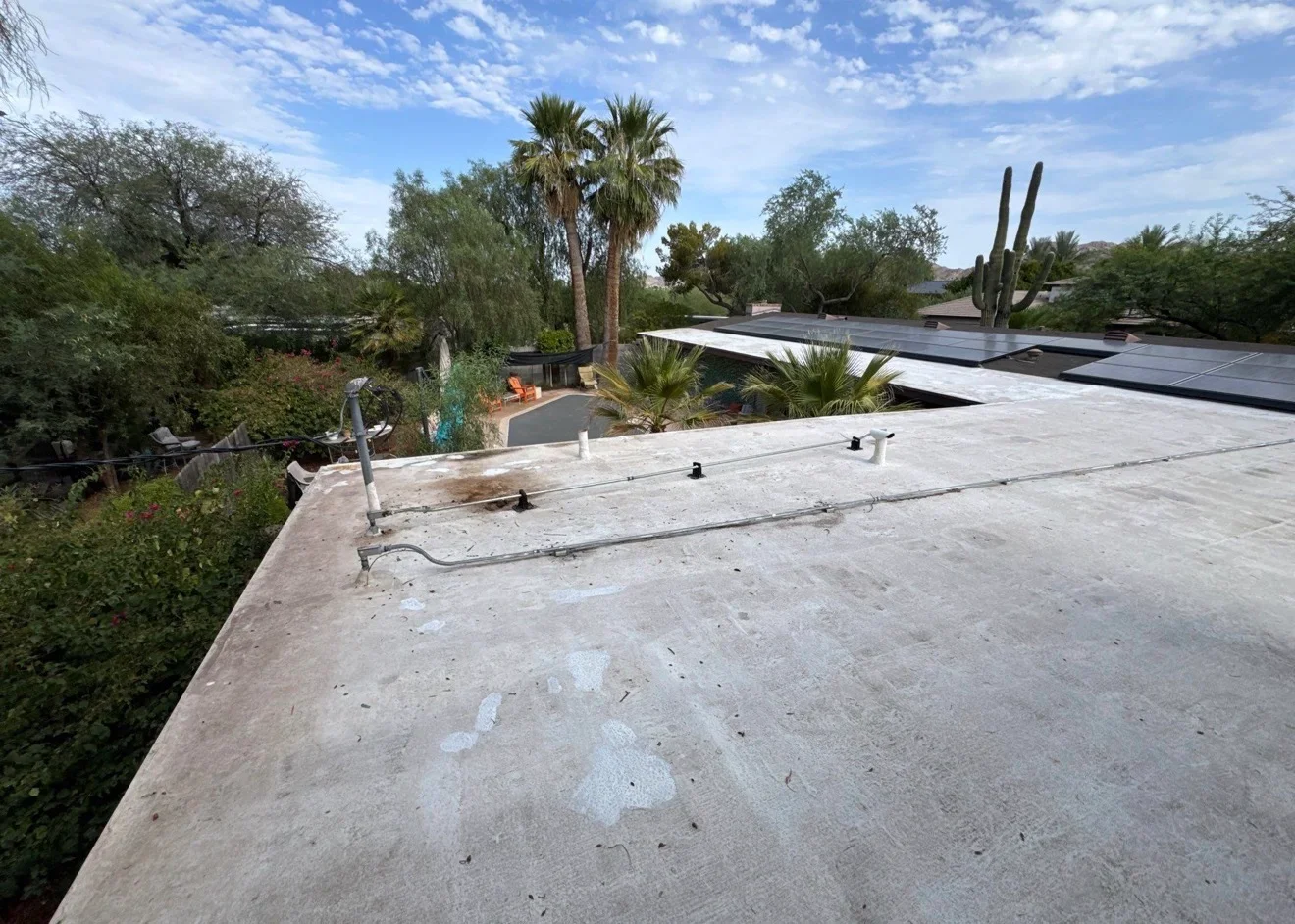 Flat concrete roof with solar panel mounts, metal conduit, and roof penetrations during installation