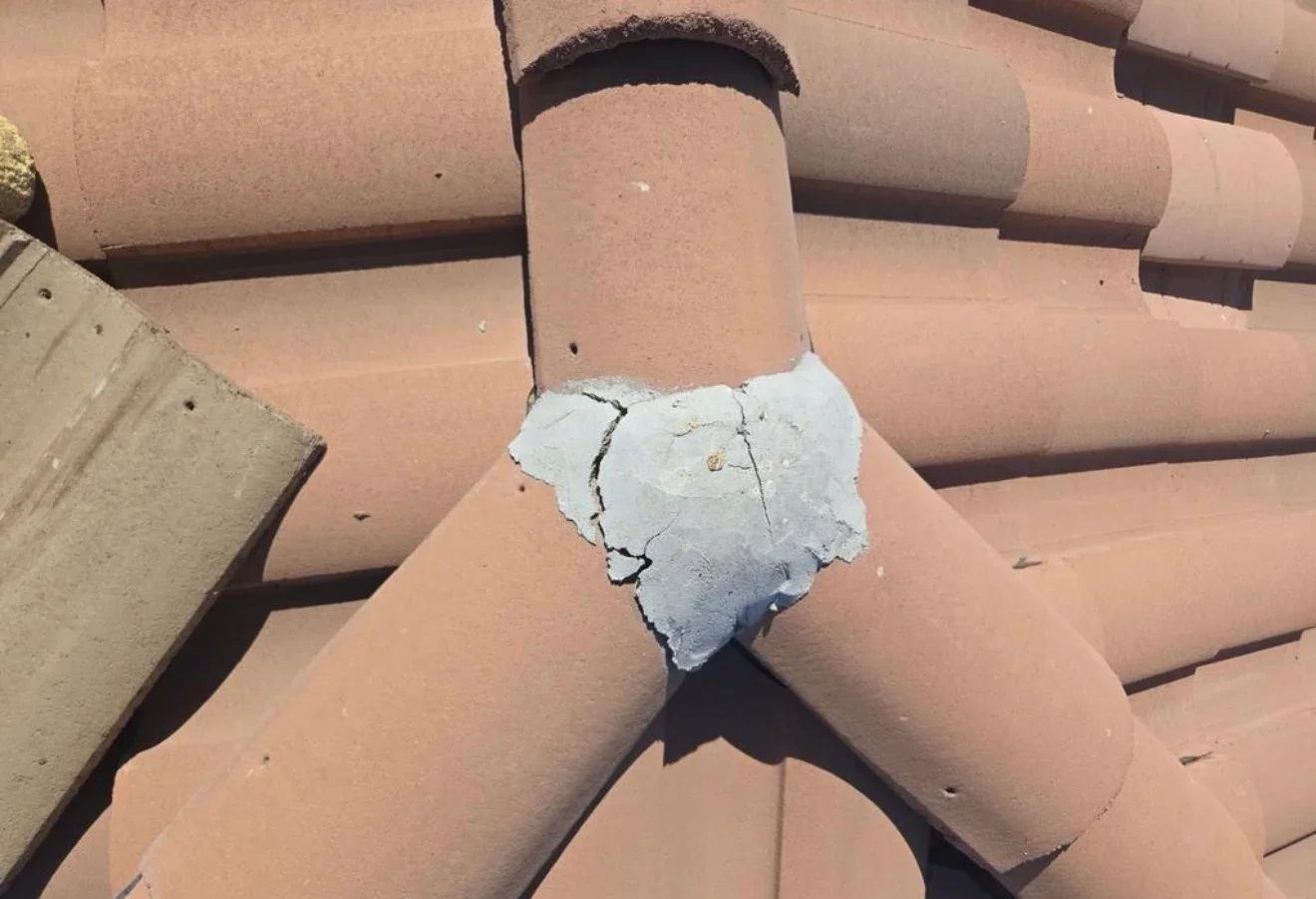 Clay barrel tiles with white cement flashing repair on roof junction