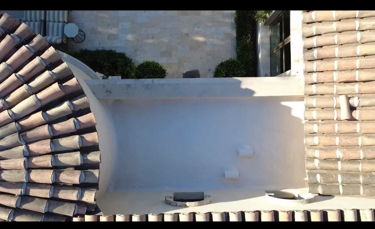 Flat roof membrane installation with clay tile roofing and brick chimney detail