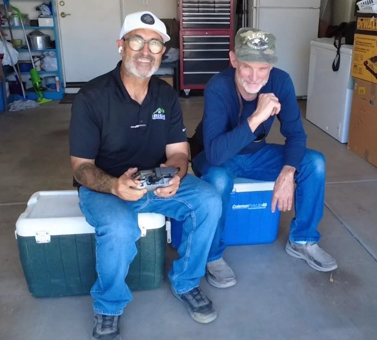 Two workers on job site with coolers and equipment in garage workspace