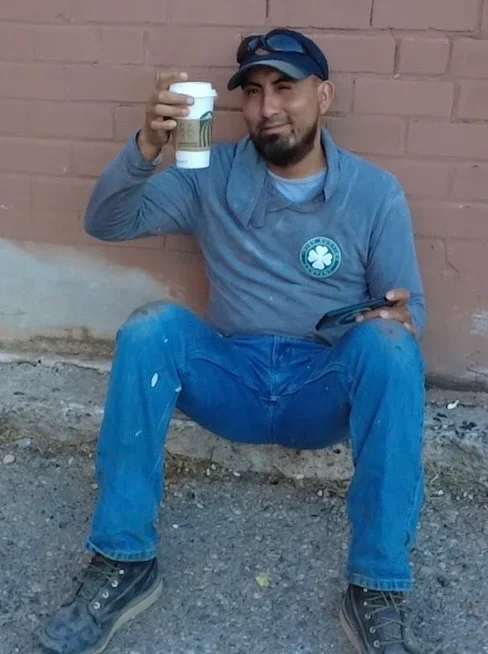 Roofing contractor holding shingle sample against brick wall during material inspection