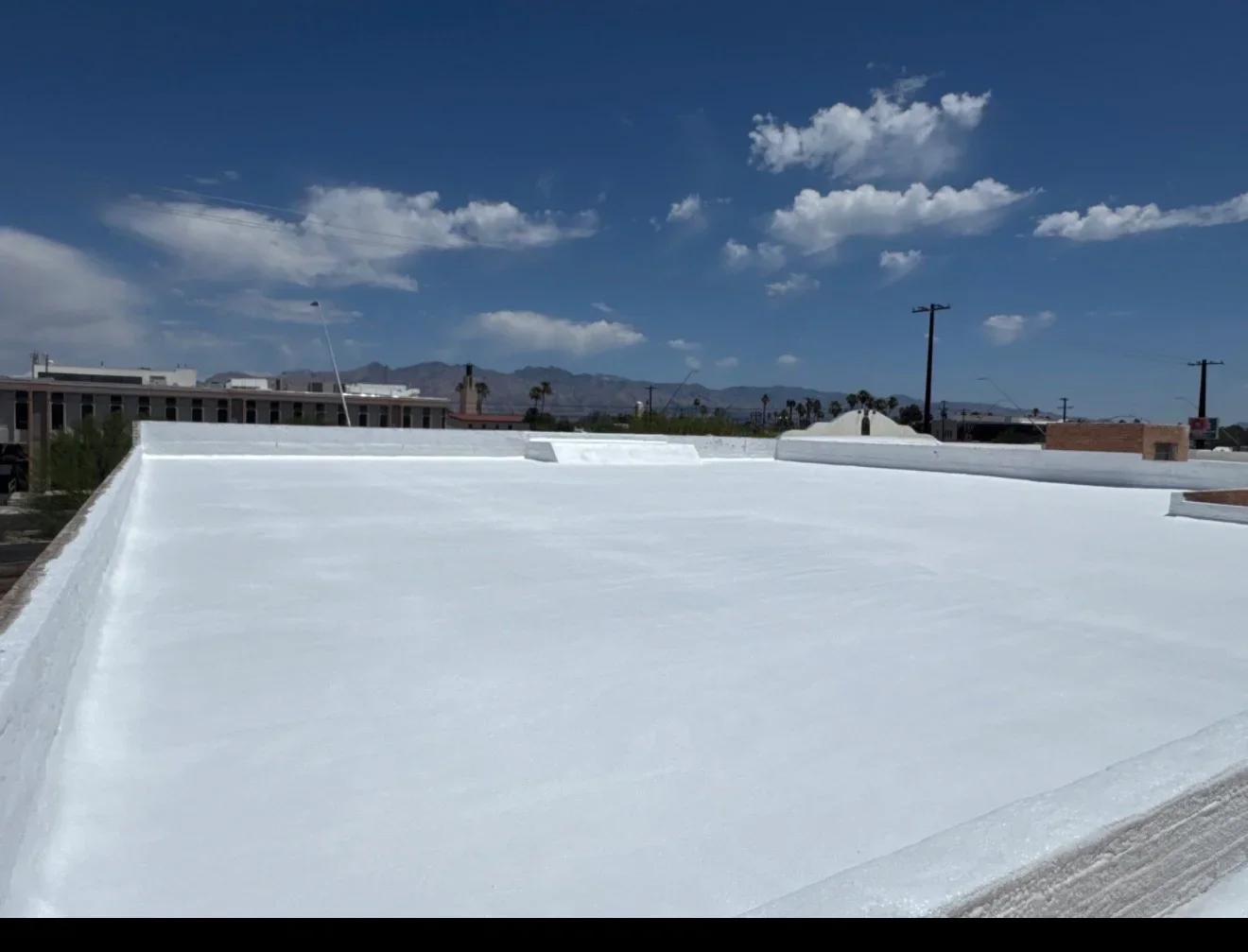 White flat roof membrane installation with edge trim and HVAC penetrations on commercial building