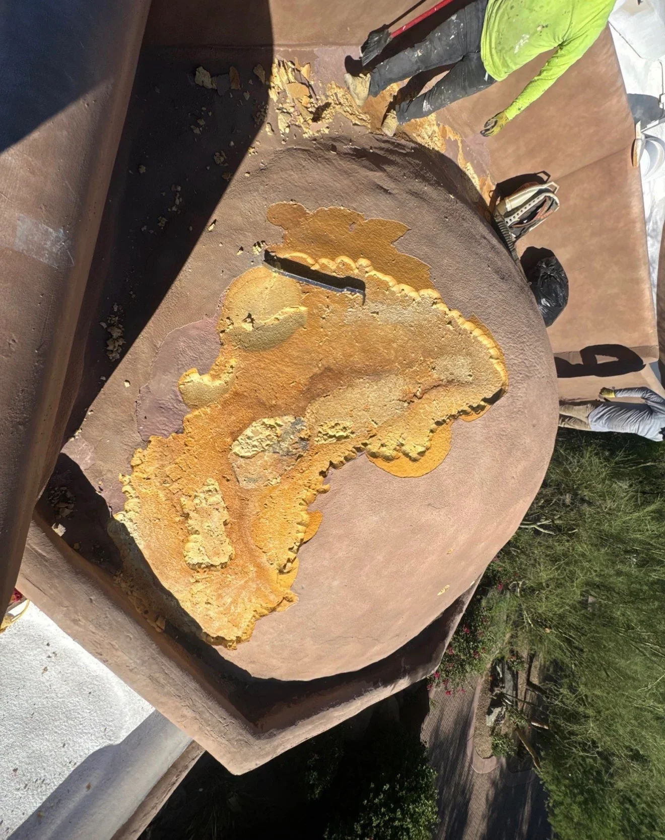 Roof patching with yellow sealant compound applied to damaged roofing material