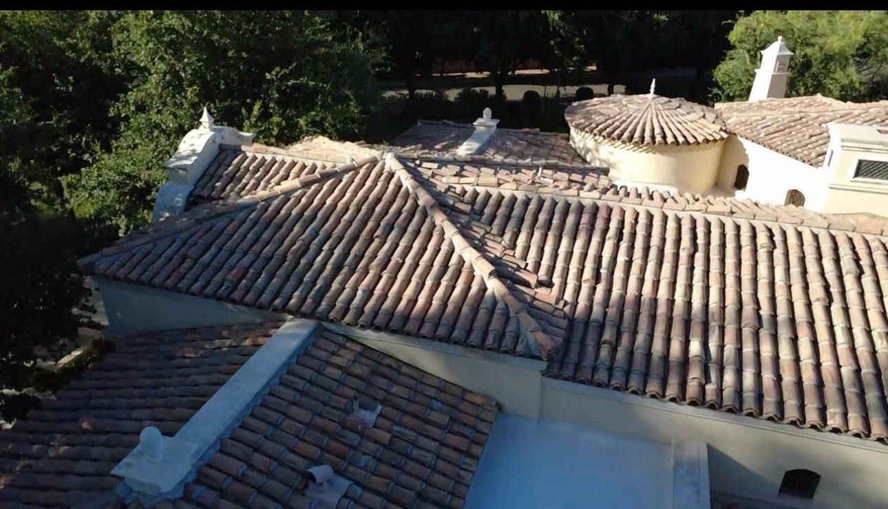 Spanish clay barrel tile roof with curved sections, terracotta tiles, and white stucco trim