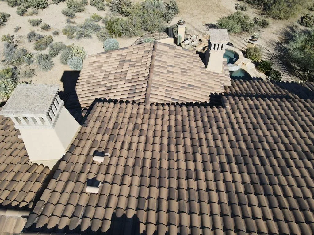 Aerial view of clay barrel tile roof with multiple slopes, white flashing, and complex roof geometry