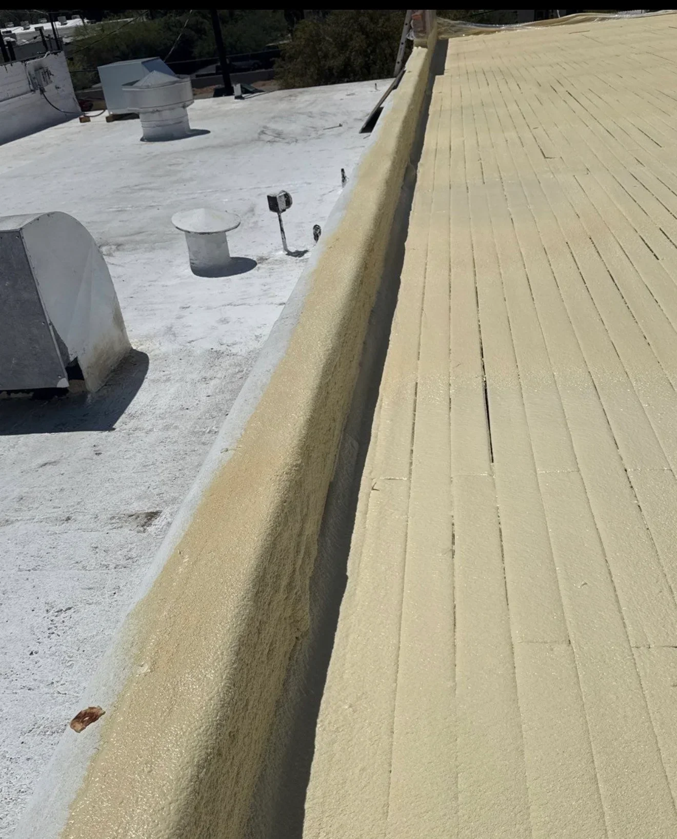 Rigid foam insulation board installed on flat roof with white membrane substrate visible