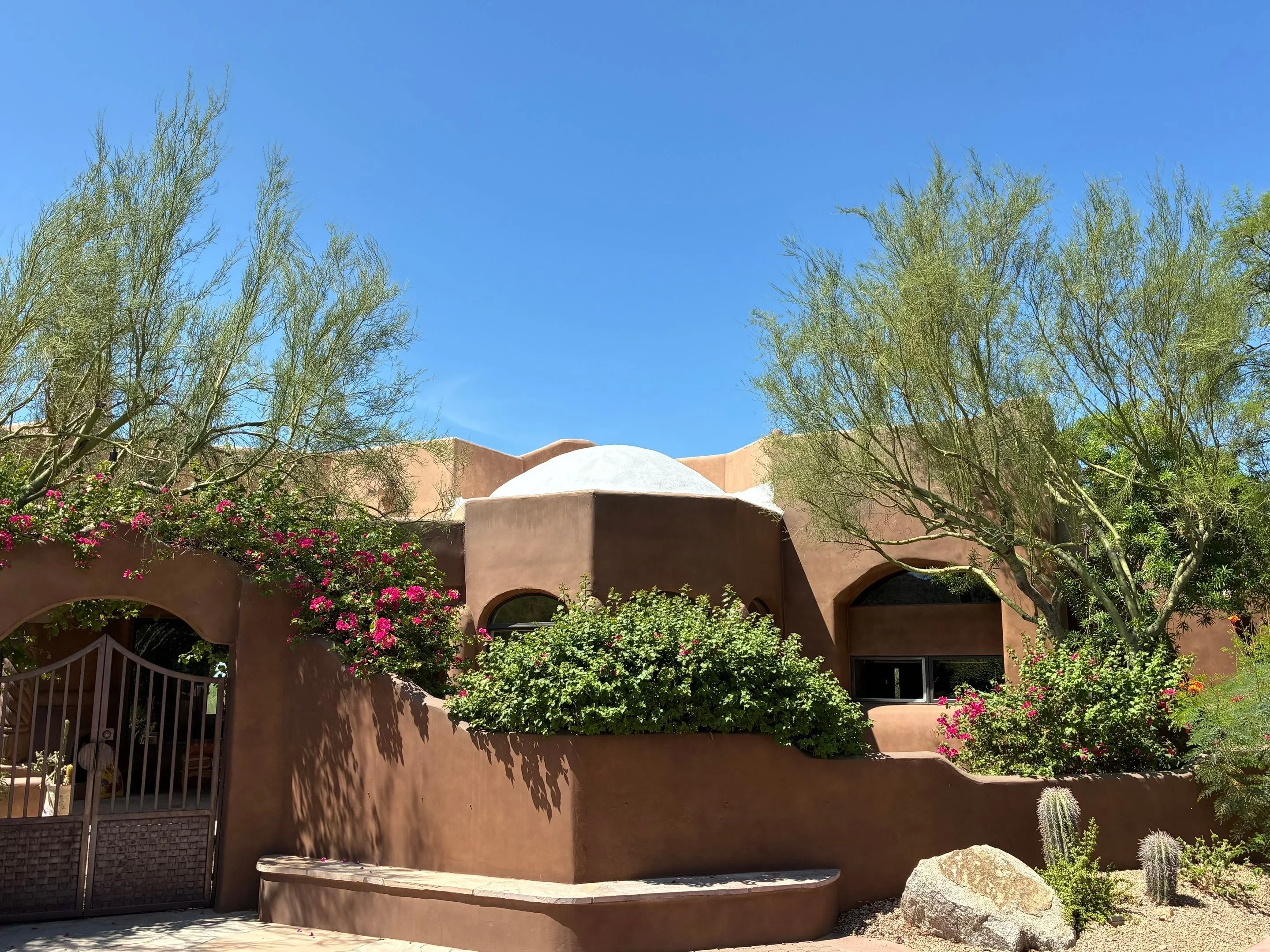 White dome roof on terracotta stucco home with curved architectural details and desert landscaping