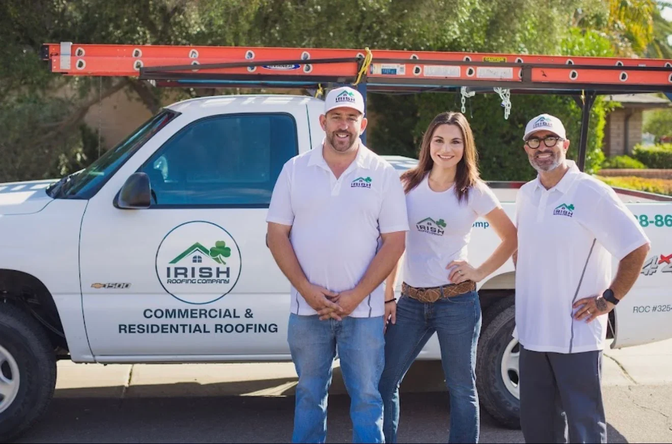 Roofing crew with white service truck equipped with red ladder rack and safety gear