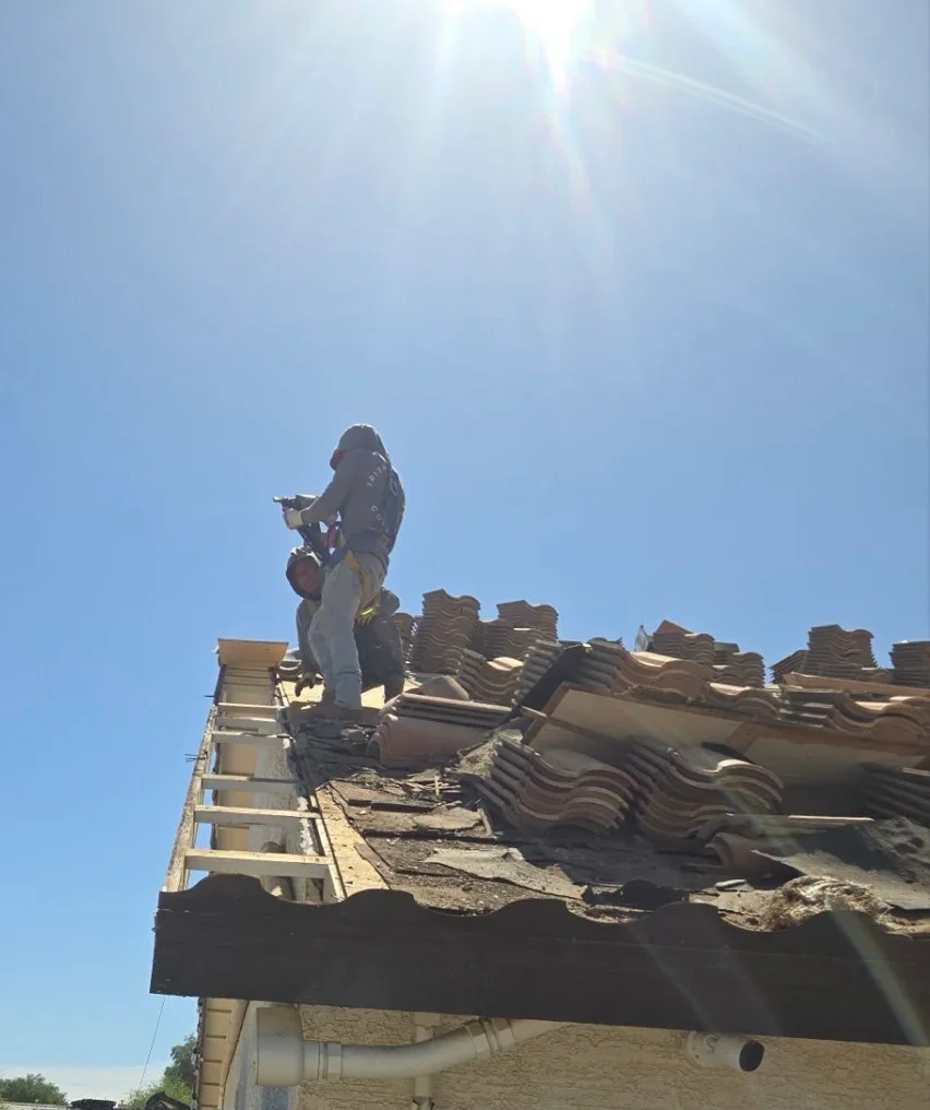 Roofer installing clay barrel tiles on residential roof with scaffolding