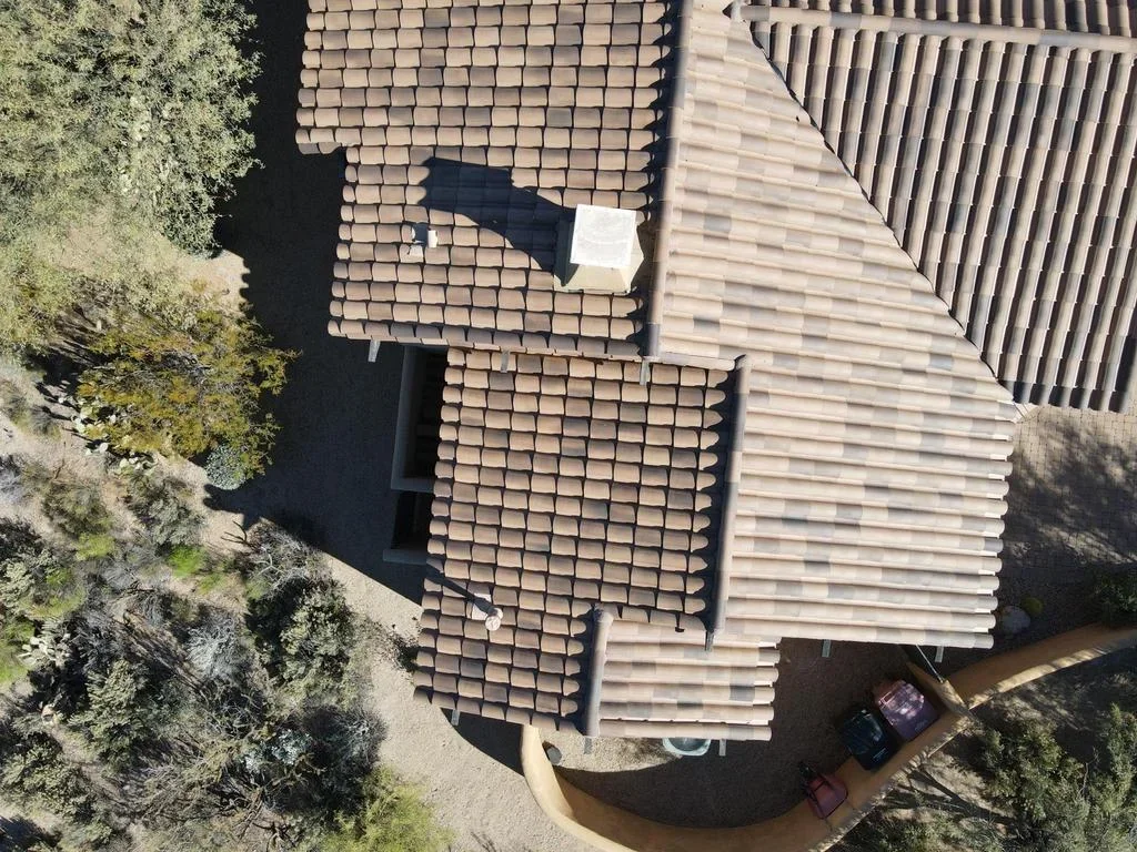 Aerial view of multi-section roof with clay tiles and composite shingles during replacement installation