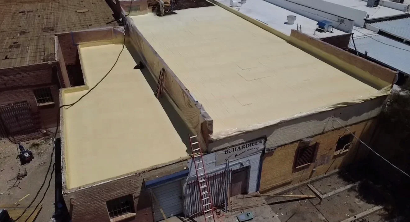 Cream-colored flat roof membrane installation with metal edge trim and flashing details