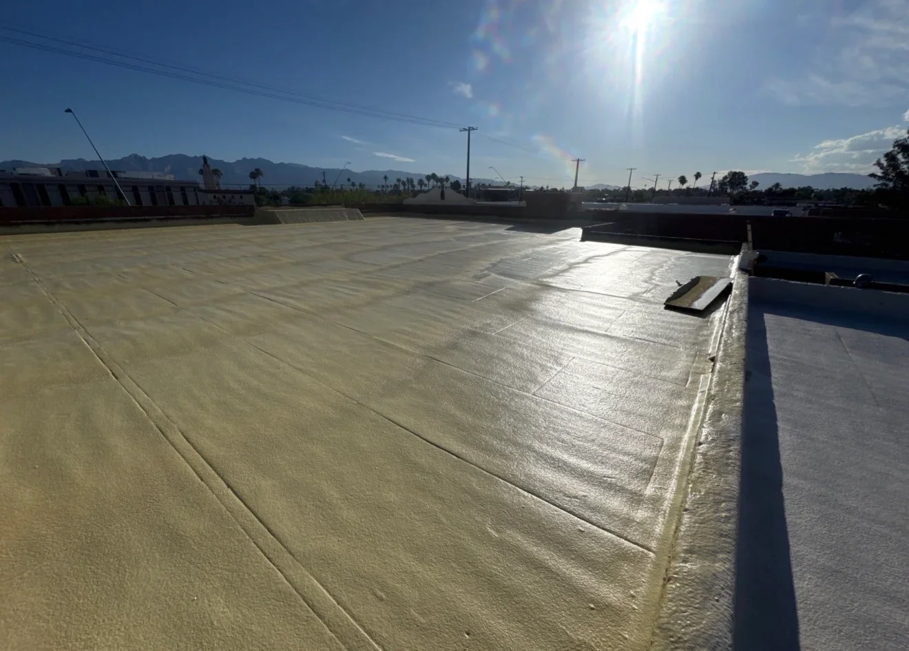 Light-colored flat roof membrane with seams and perimeter flashing on commercial building