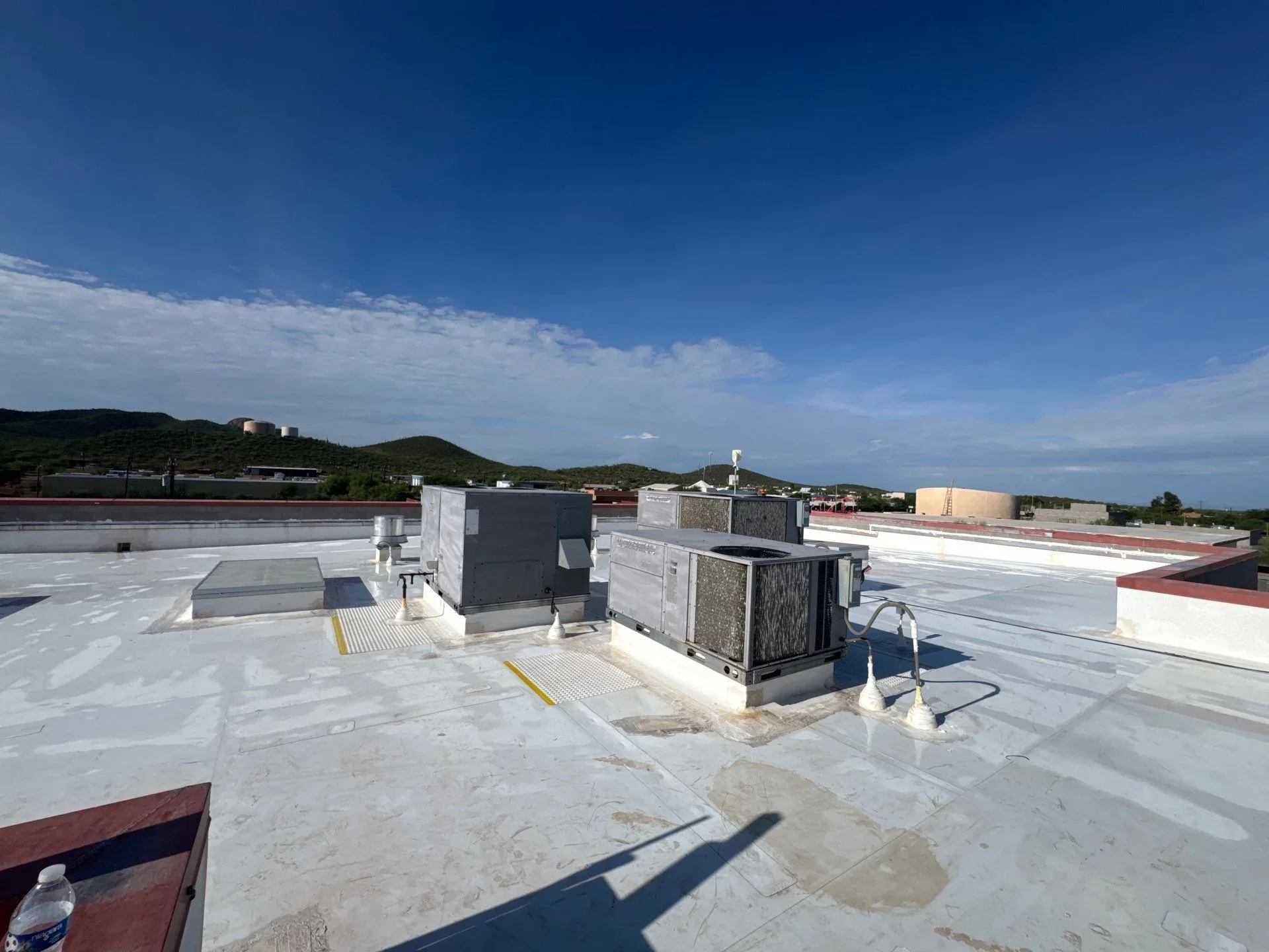 Commercial flat roof with white membrane, HVAC units, and mechanical equipment platforms