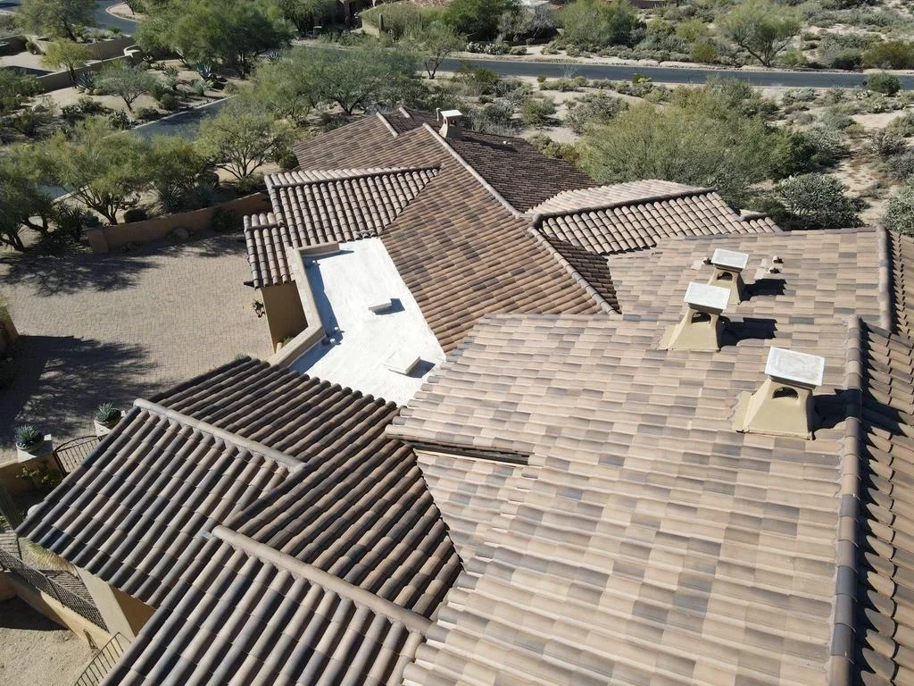 Aerial view of completed multi-section residential roof with architectural shingles, skylights, and varied roof planes