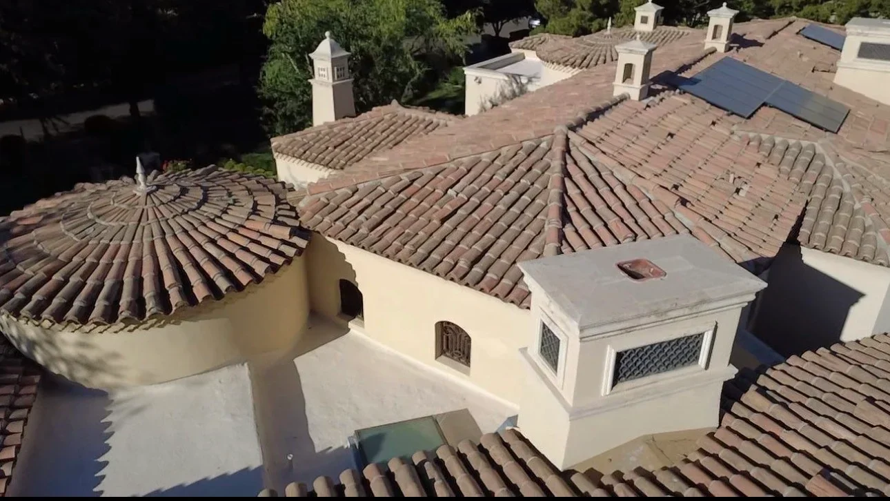 Aerial view of Spanish clay tile roofing installation on residential structures with white stucco walls