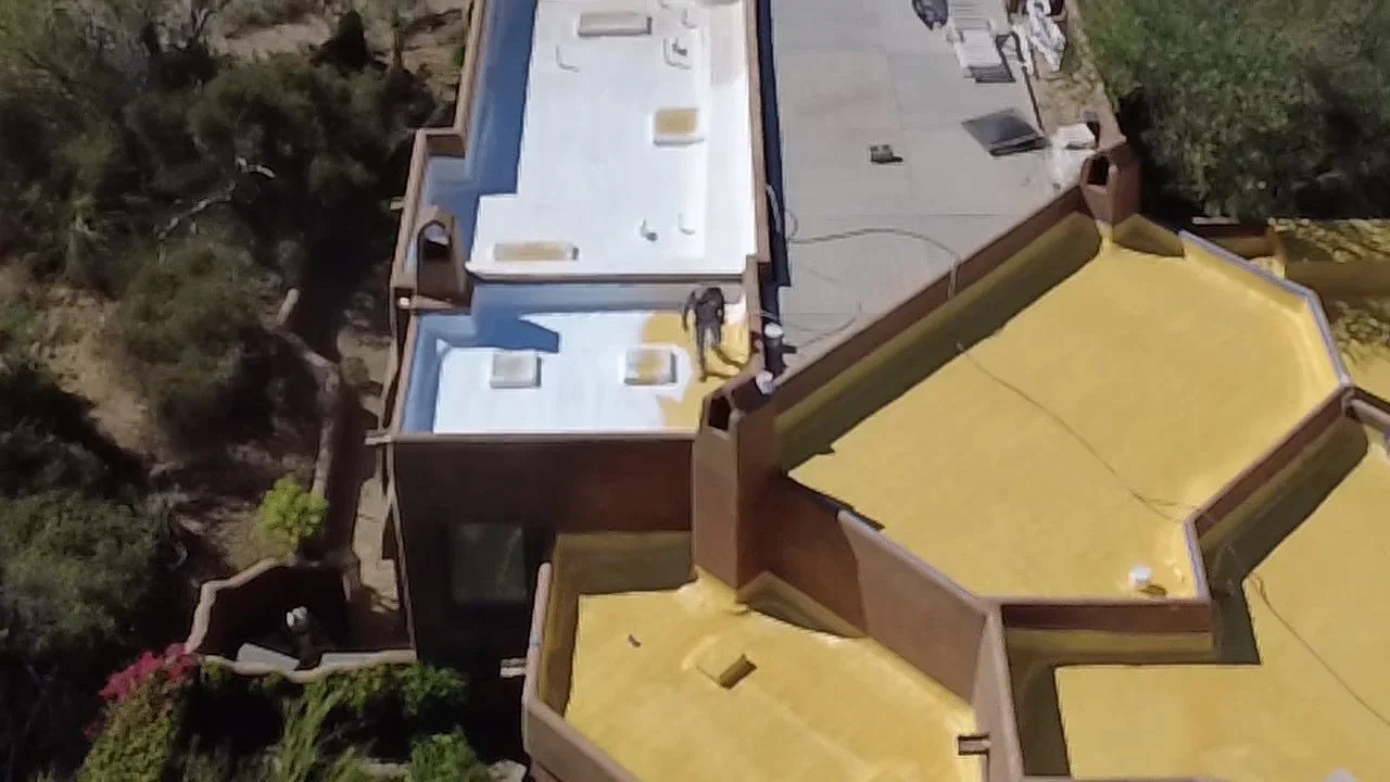 Aerial view of flat roof with white membrane, vents, and roof penetrations installed