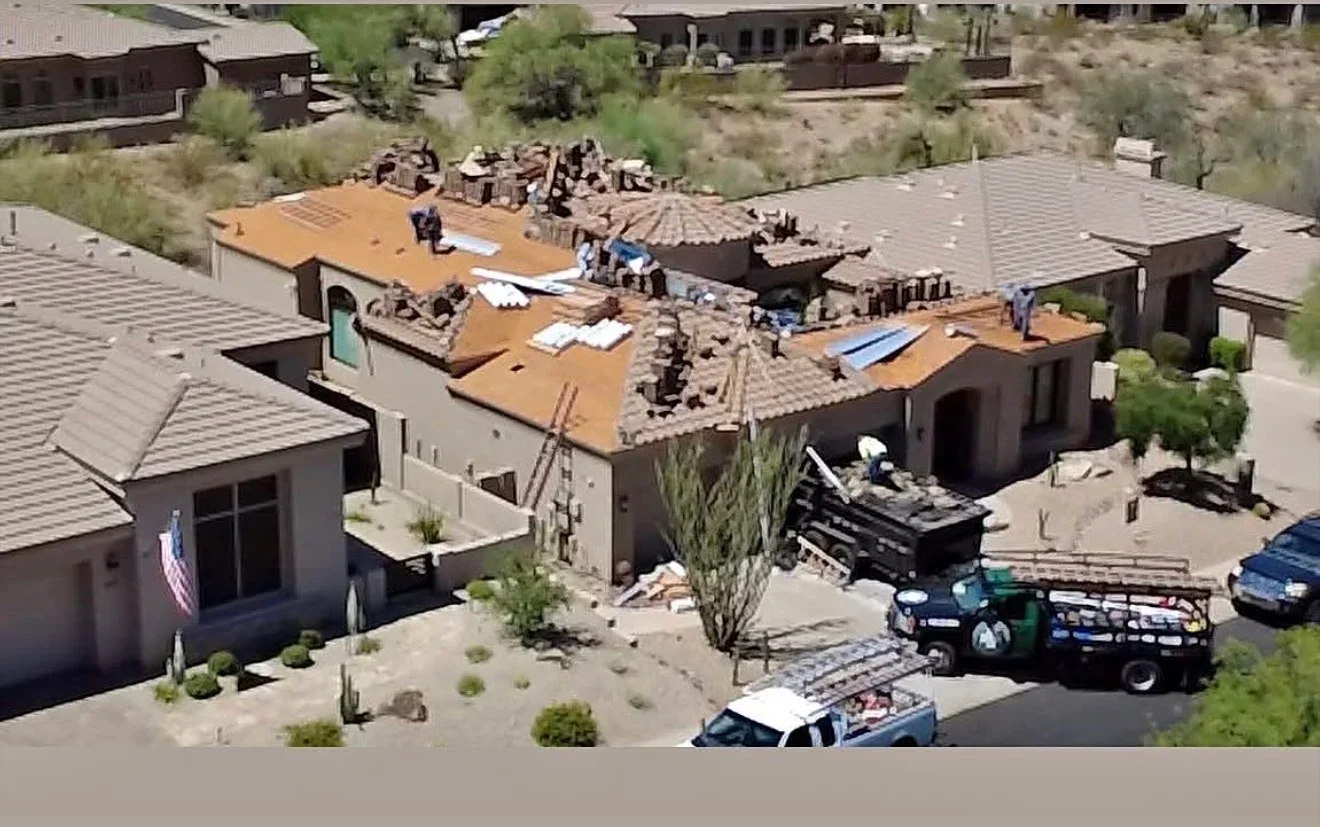 Aerial view of multi-building roof replacement with old tile removal and new shingle installation in progress