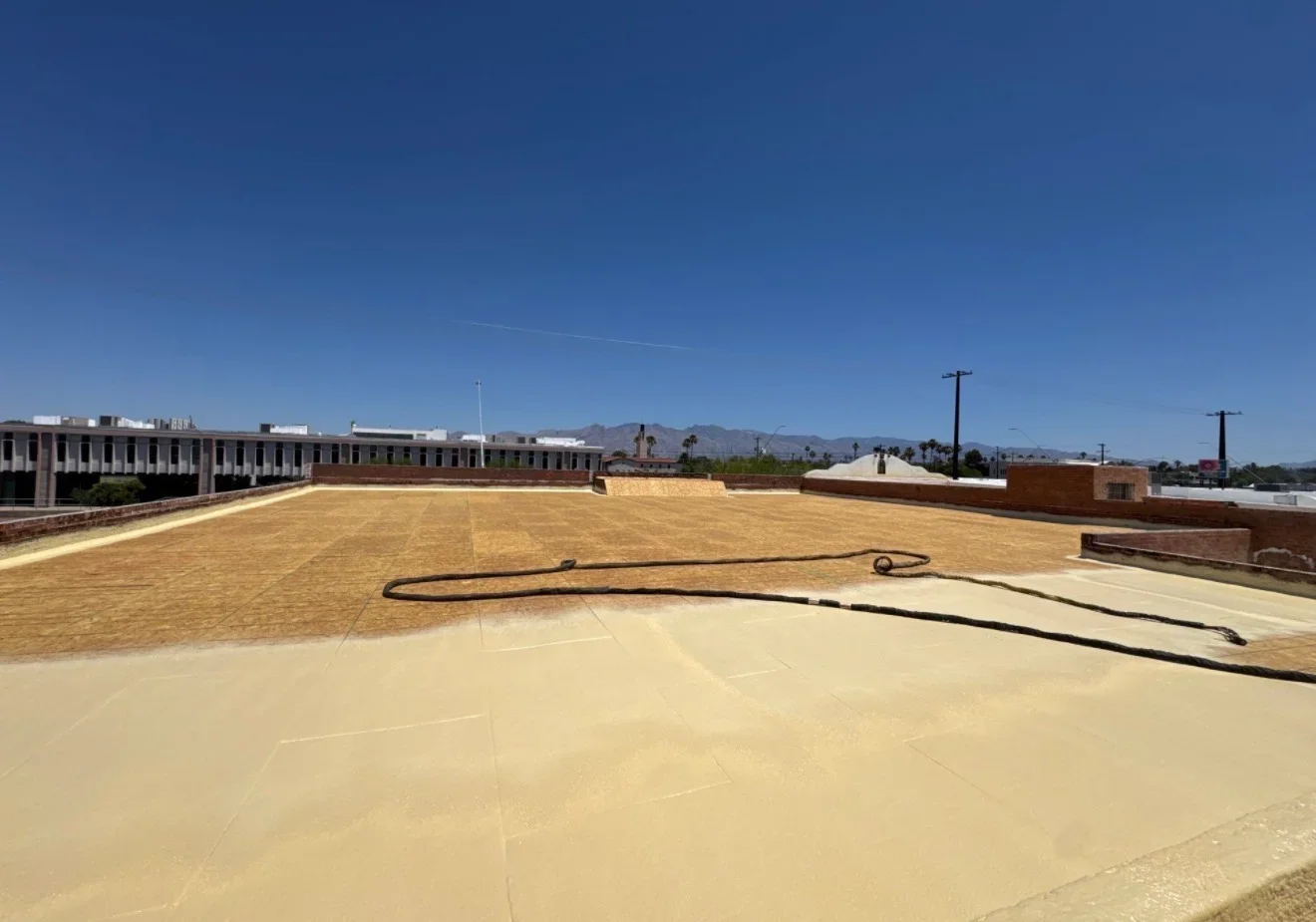 Commercial flat roof with tan membrane, seams, and metal edge trim during installation