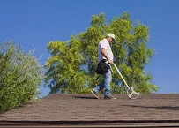 Technician cleaning asphalt shingle roof with pressure washing equipment