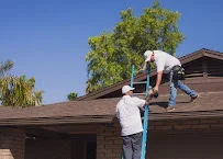 Roofer inspecting composite shingle roof on residential home