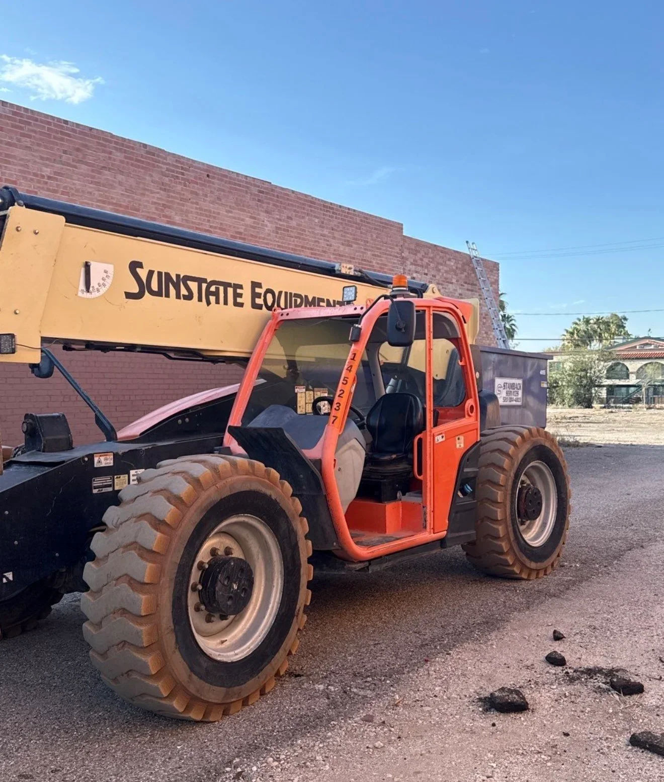 Red telehandler with large tires and open cab for elevated material handling and access
