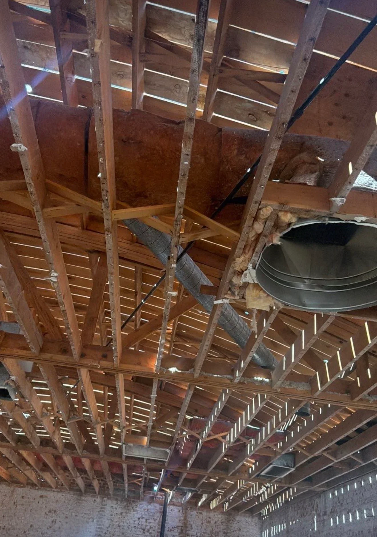 Wooden roof framing with metal strapping, joists, and HVAC ductwork installation