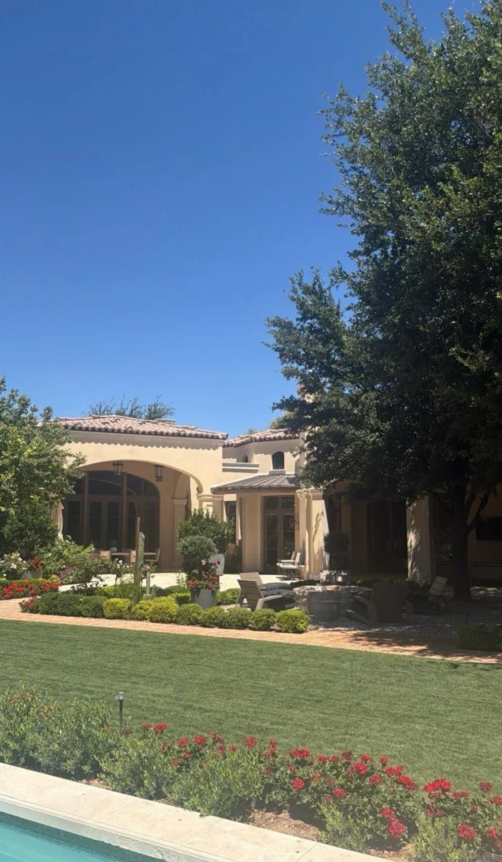 Spanish Colonial home with clay barrel tile roof, arched portico, and manicured courtyard landscaping