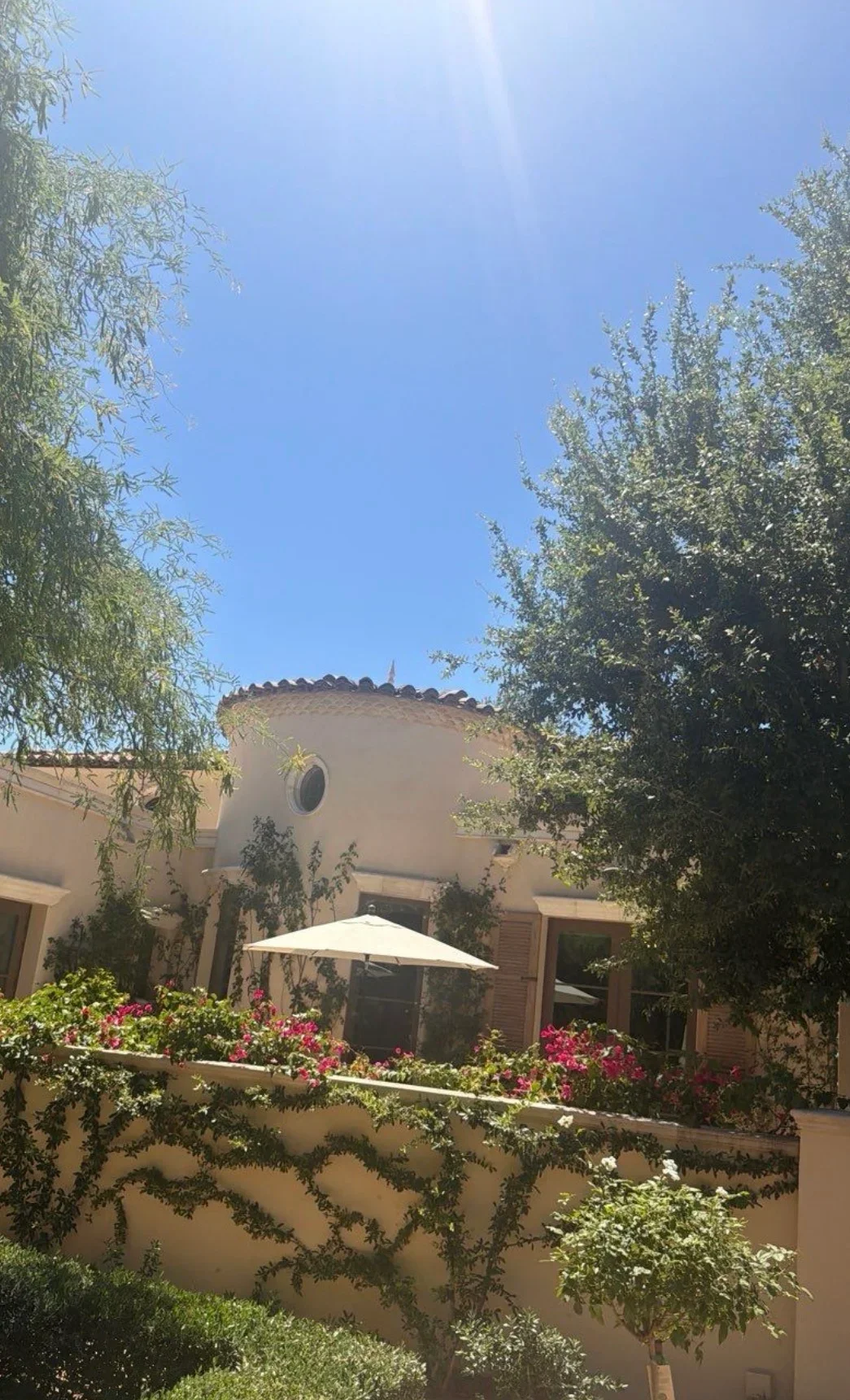 Clay tile roof with scalloped edges on stucco home, surrounded by landscaping and mature trees