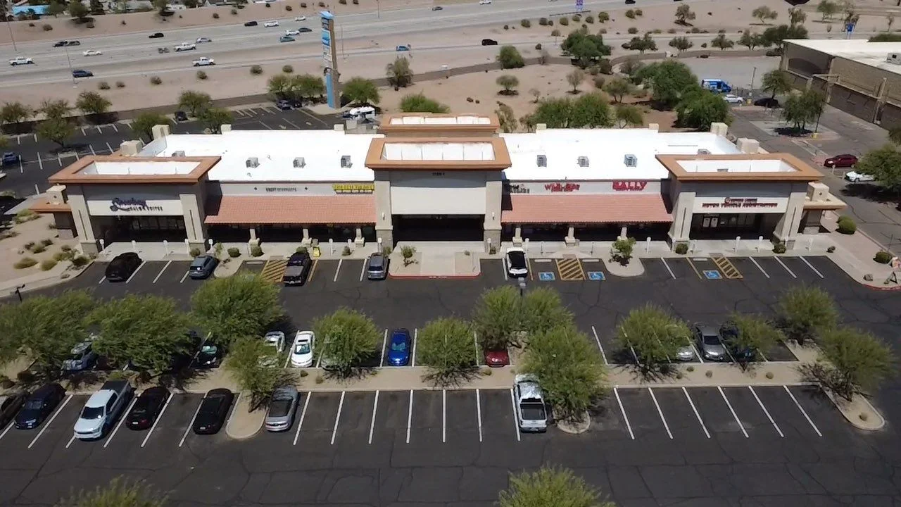 Aerial view of commercial retail building with white flat roof, copper trim details, and new skylights