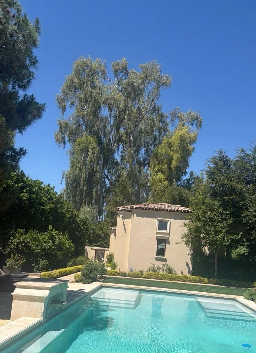 Clay tile roof installation on stucco residential building with pool and landscaping
