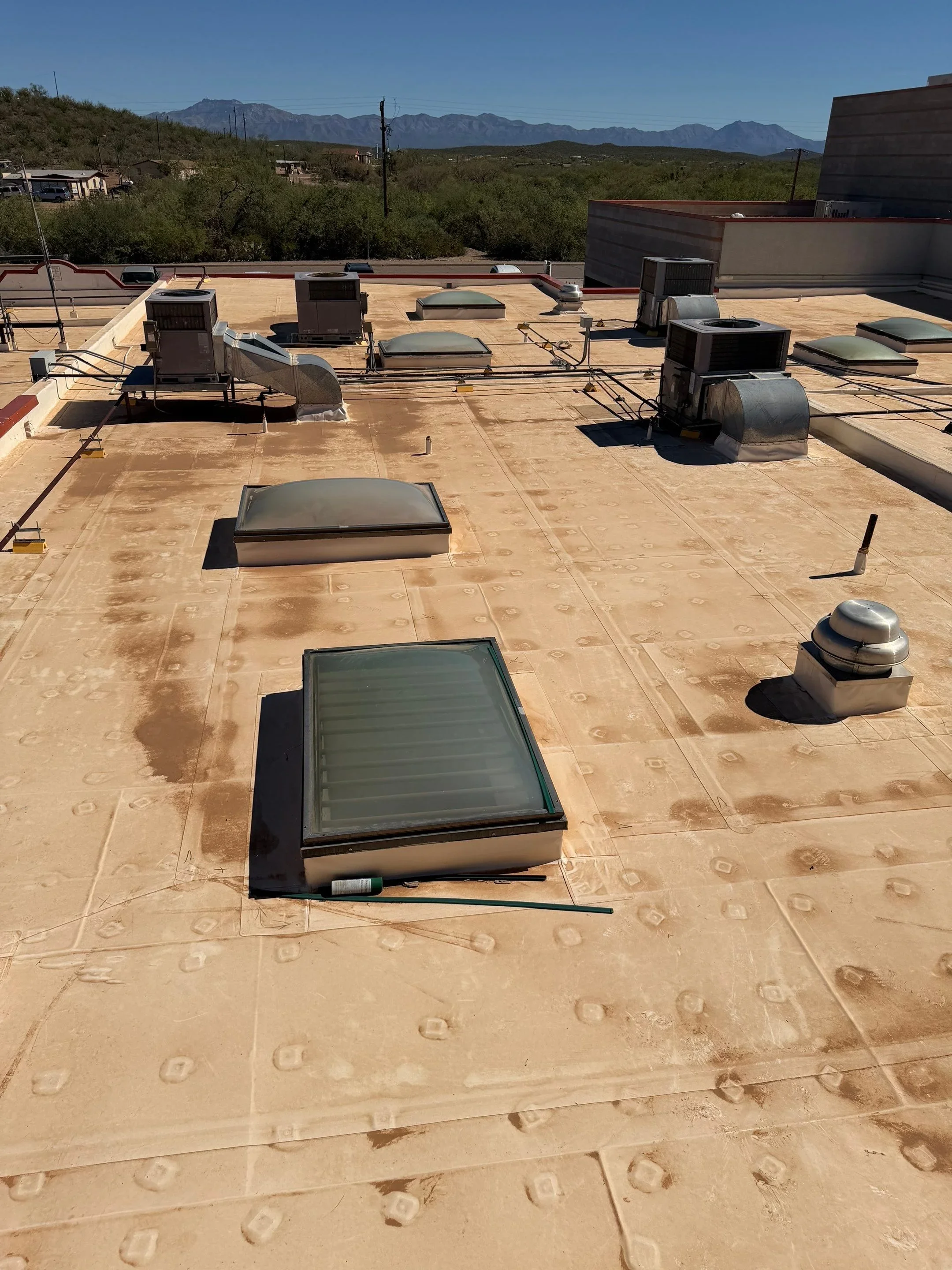 Flat roof with installed skylights, membrane seams, and HVAC equipment on commercial building