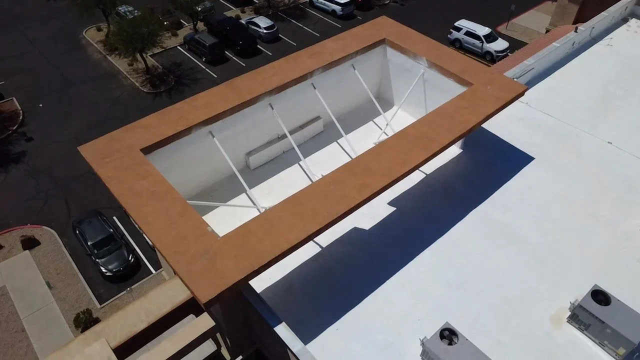Aerial view of commercial roof with copper-framed skylight opening and white interior framing