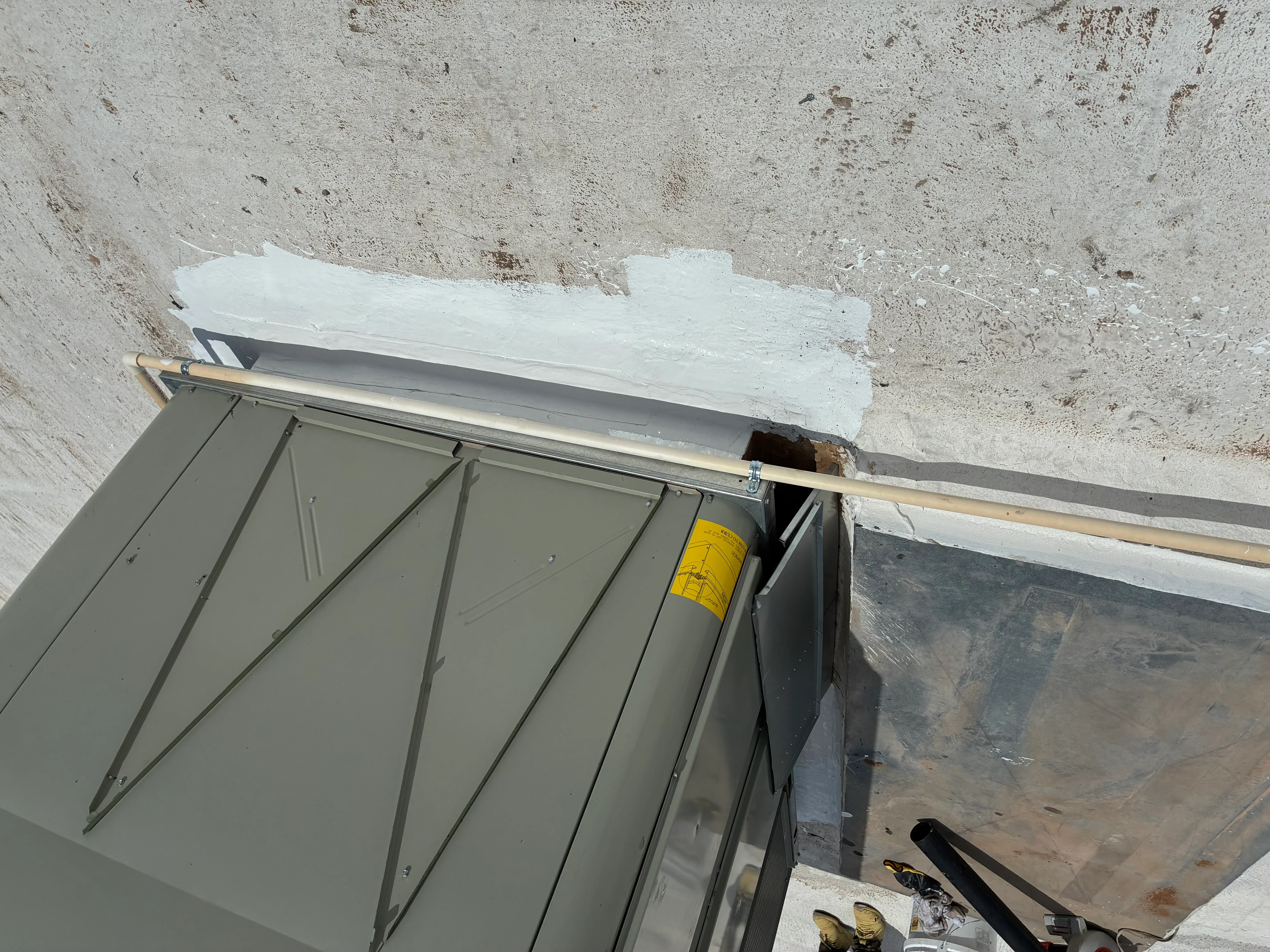 Standing seam metal roof panels installed with vertical seams and yellow fasteners at roof edge