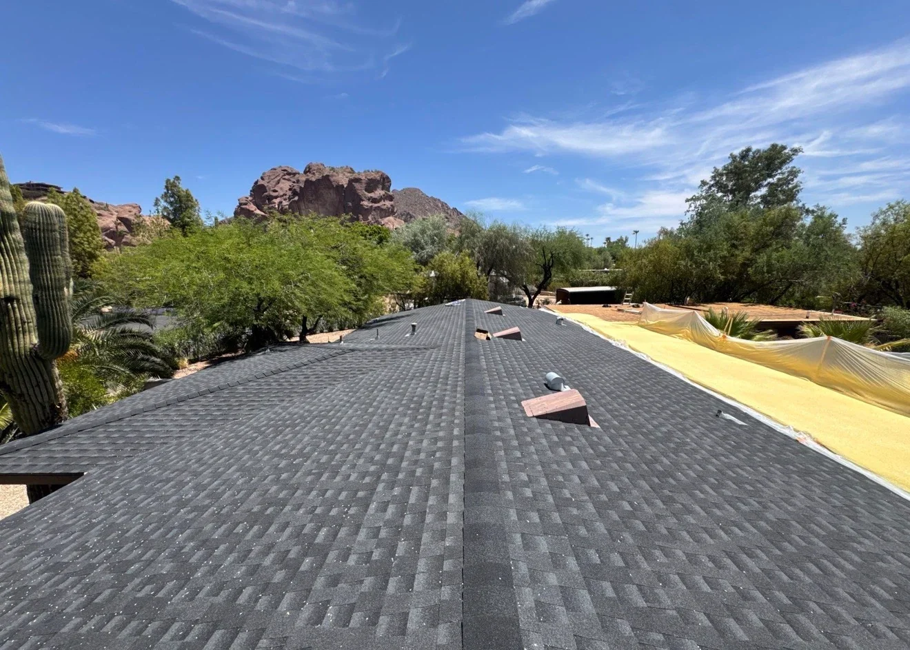 Charcoal gray architectural shingles installed on large residential roof with ridge vents and proper alignment