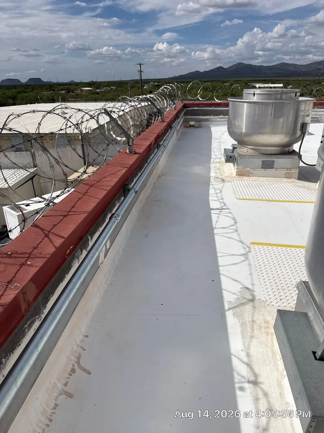 Flat roof with white membrane, metal trim, safety railings, and HVAC equipment on commercial building