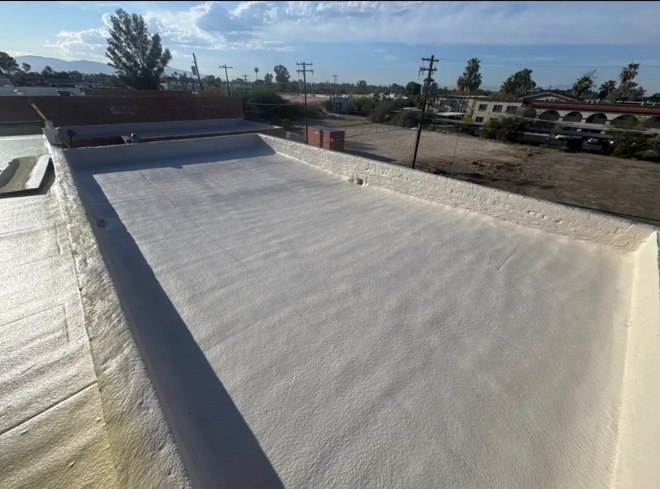 Light-colored TPO membrane flat roof installation with sealed perimeter edges and parapet walls