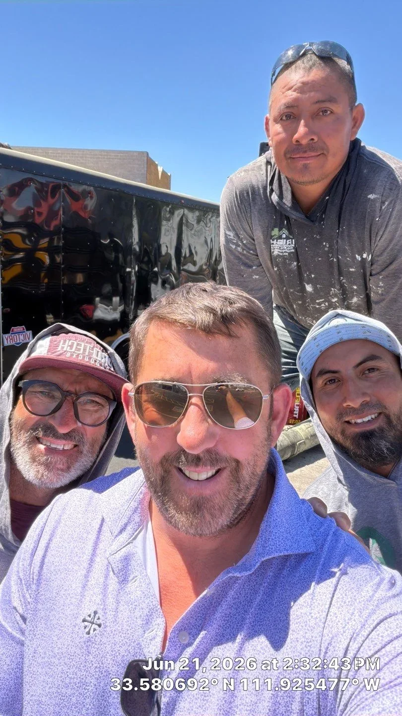 Roofing crew team photo at commercial job site with equipment trailer