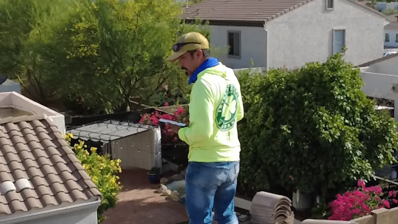 Roofing contractor inspecting clay tile roof on residential home with landscaping
