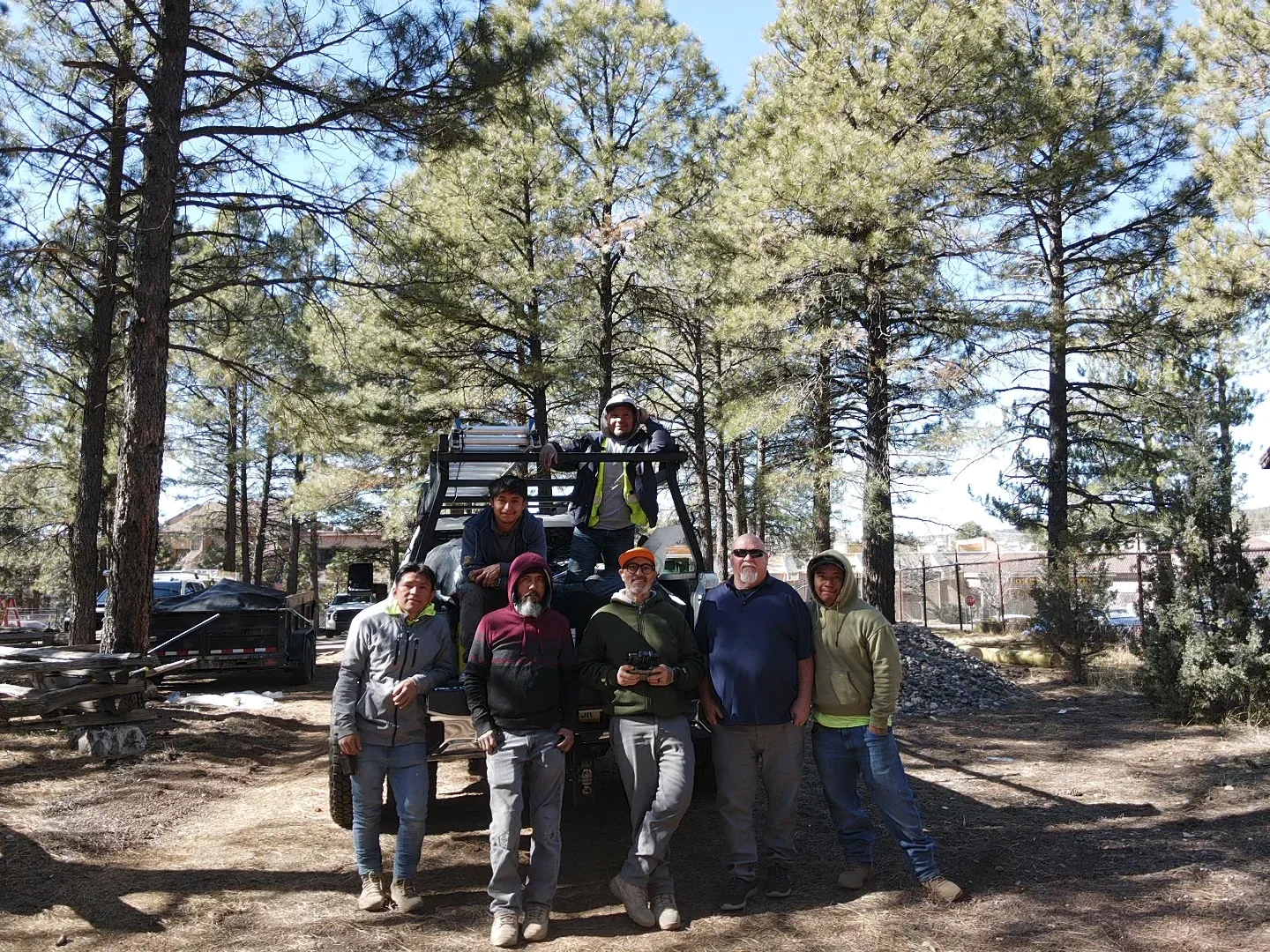 Roofing crew team photo with flatbed truck in forested area