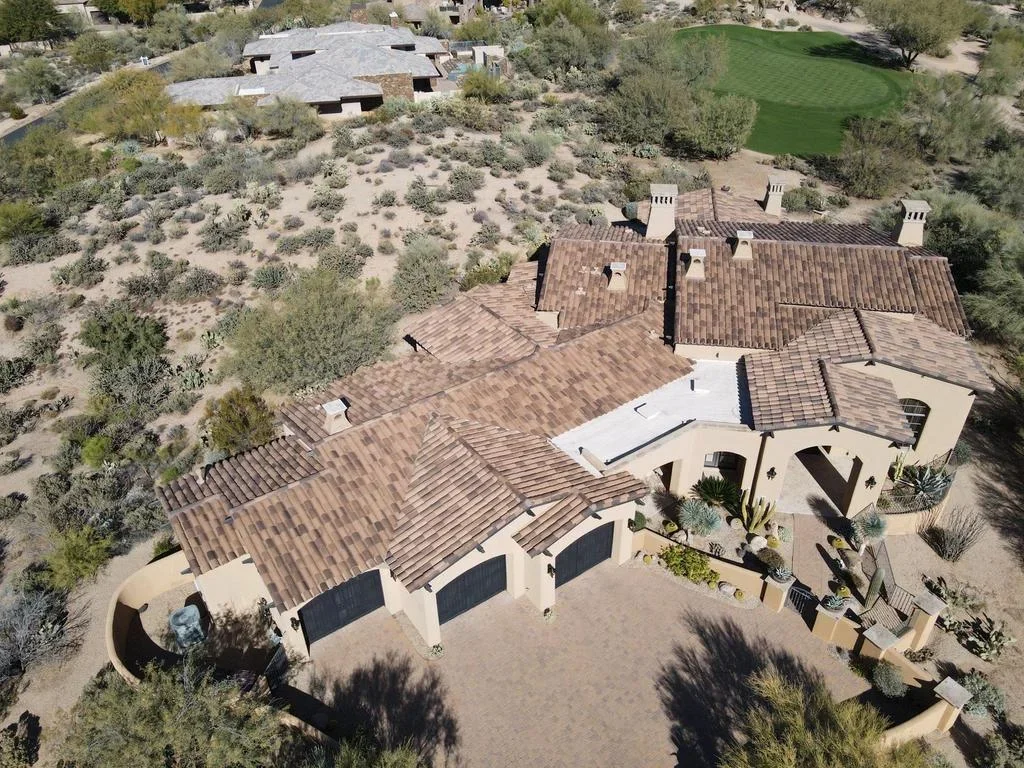 Aerial view of residential roof with brown architectural shingles, multiple peaks, and ridge vents