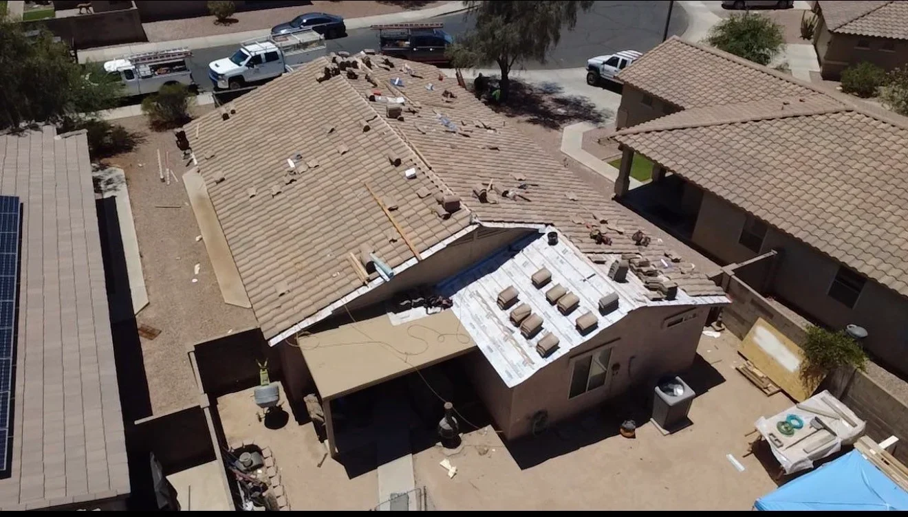 Aerial view of residential roof replacement with old shingles removed and new materials staged for installation