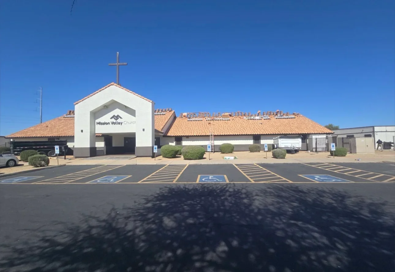 Clay tile roof installation on church building with cross, terracotta tiles, multiple roof sections